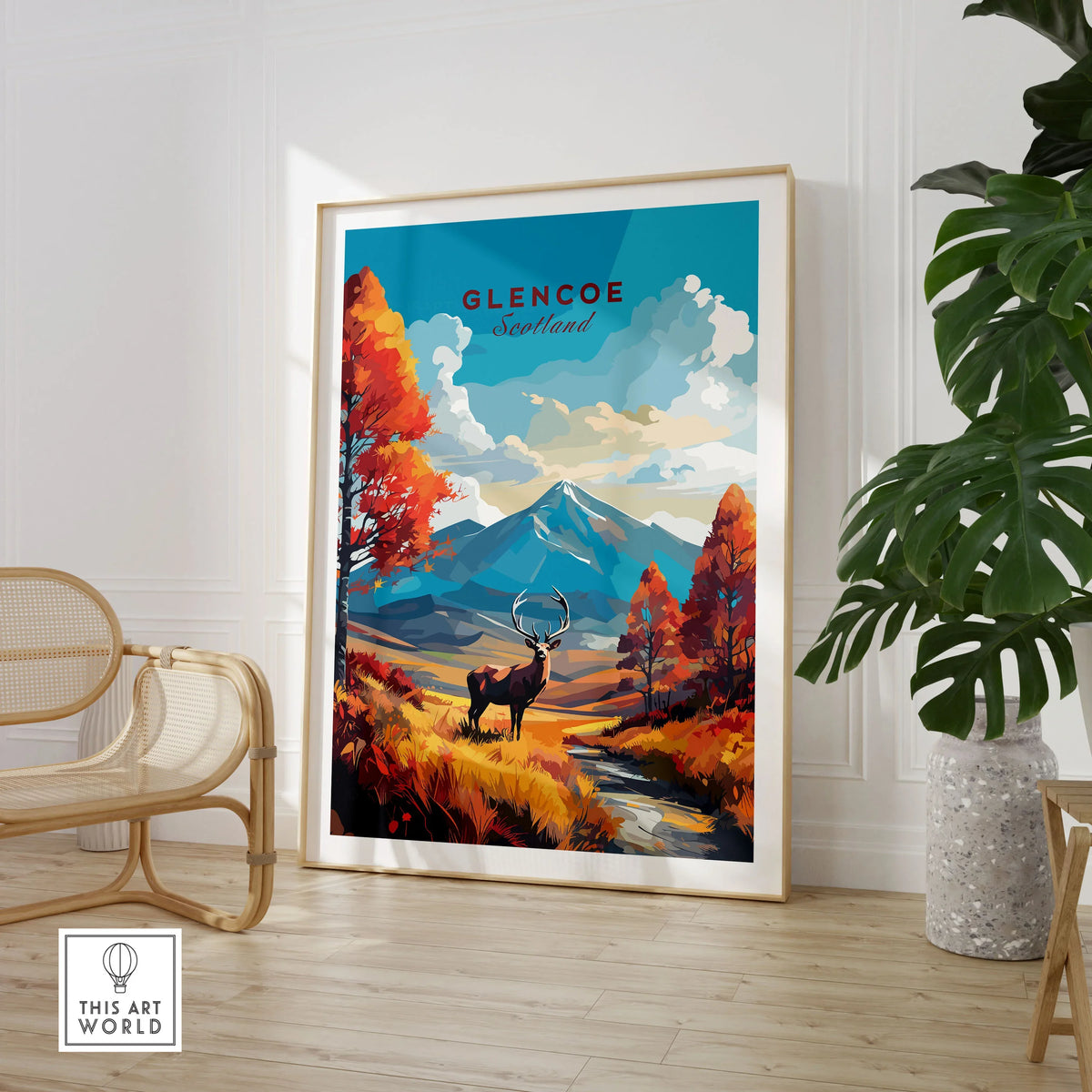 Glencoe Art Print in a large natural wood frame leaning in a room with a rattan chair and monstera plant