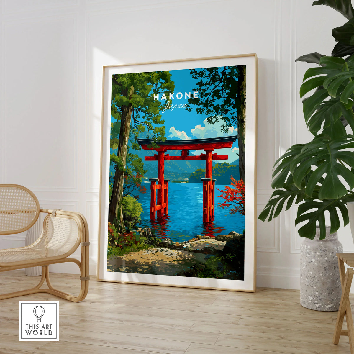 Hakone Japan Lake Ashi Torii Gate Poster - Floating Gate Wall Art in a large natural wood frame leaning in a room with a rattan chair and monstera plant