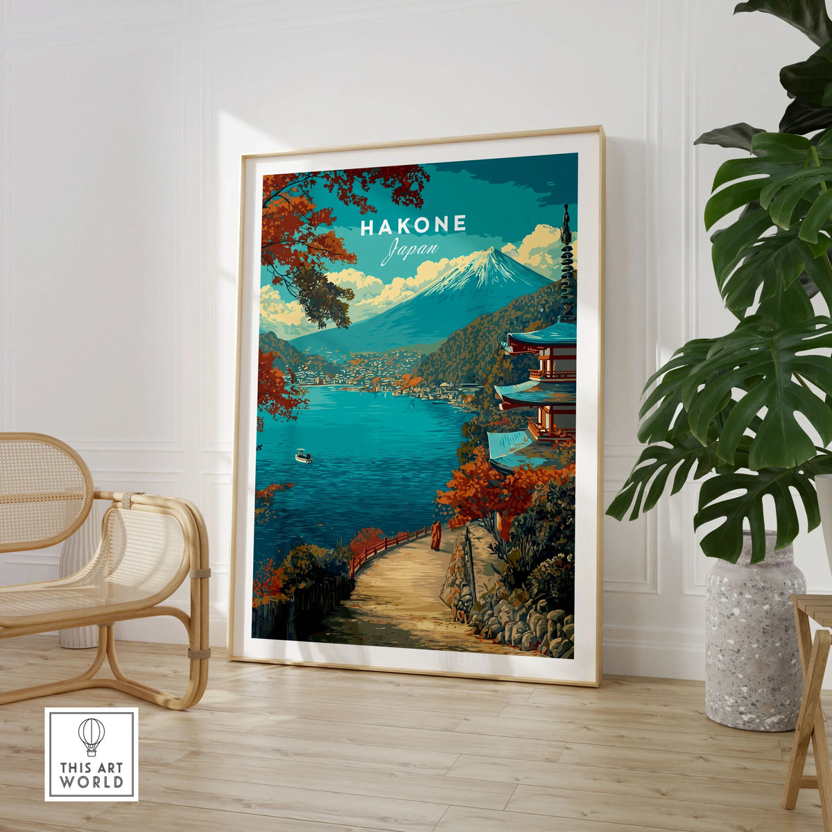 Hakone Print Japan Lake View Pagoda - Mount Fuji Scenic Poster in a large natural wood frame leaning in a room with a rattan chair and monstera plant