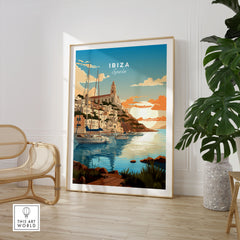 Ibiza Poster Print in a large natural wood frame leaning in a room with a rattan chair and monstera plant