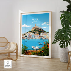 Ibiza Print in a large natural wood frame leaning in a room with a rattan chair and monstera plant