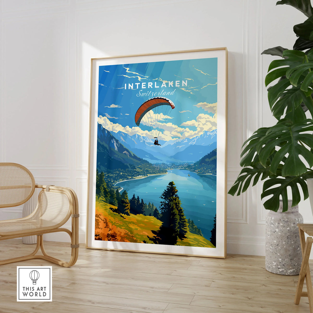 Interlaken Switzerland Poster in a large natural wood frame leaning in a room with a rattan chair and monstera plant