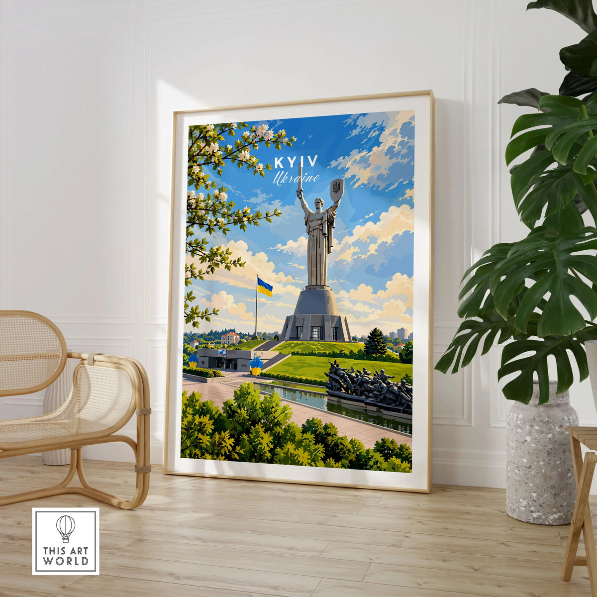 Kyiv Ukraine Motherland Monument Travel Poster — the Motherland Monument under spring blossom with the Ukrainian flag flying, shown as large framed print room setting chair plant
