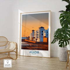 Agadir Morocco Wall Art in a large natural wood frame leaning in a room with a rattan chair and monstera plant