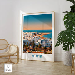 Agadir Morocco Wall Art – Mediterranean Canvas Art in a large natural wood frame leaning in a room with a rattan chair and monstera plant
