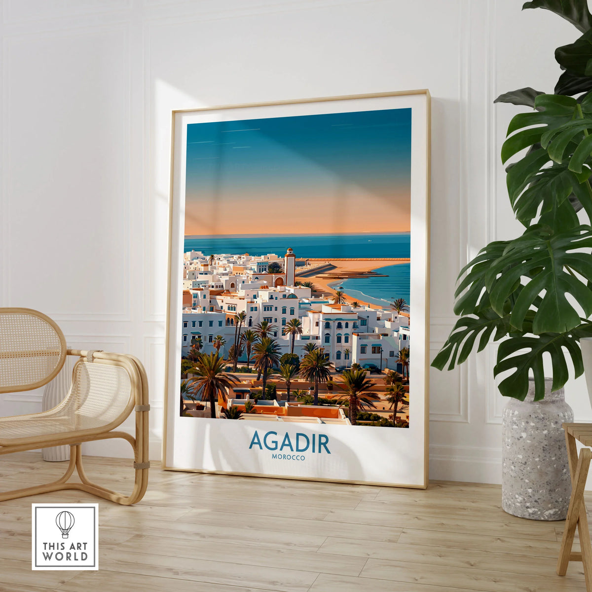 Agadir Morocco Wall Art – Mediterranean Canvas Art in a large natural wood frame leaning in a room with a rattan chair and monstera plant