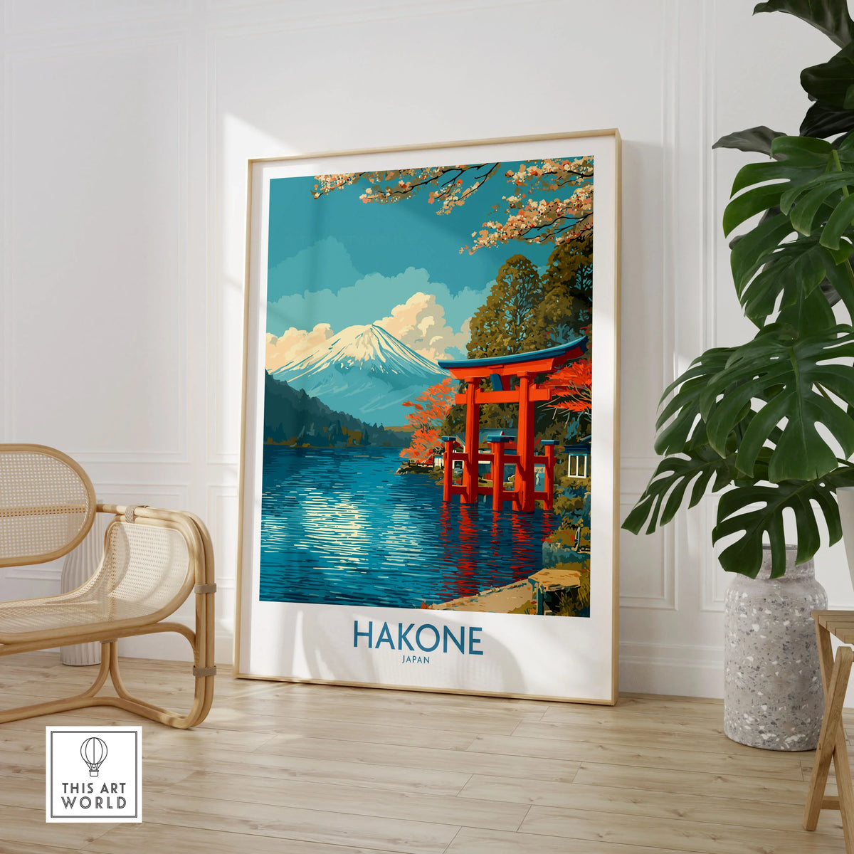 Hakone Wall Art Japan Red Torii Gate Poster in a large natural wood frame leaning in a room with a rattan chair and monstera plant