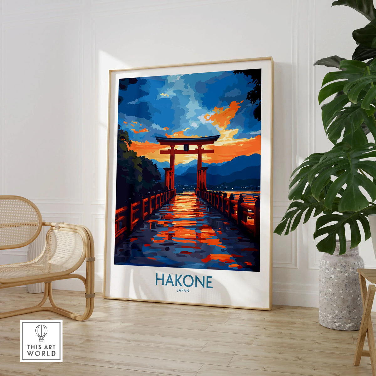 Hakone Wall Art - Japan Travel Poster in a large natural wood frame leaning in a room with a rattan chair and monstera plant