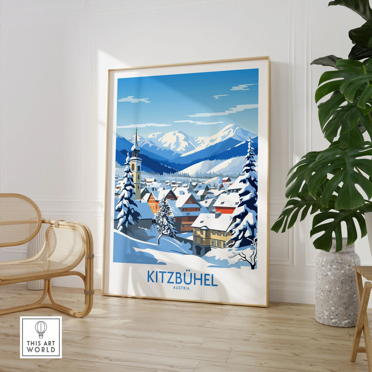 Kitzbuhel Austria Art Print in a large natural wood frame leaning in a room with a rattan chair and monstera plant