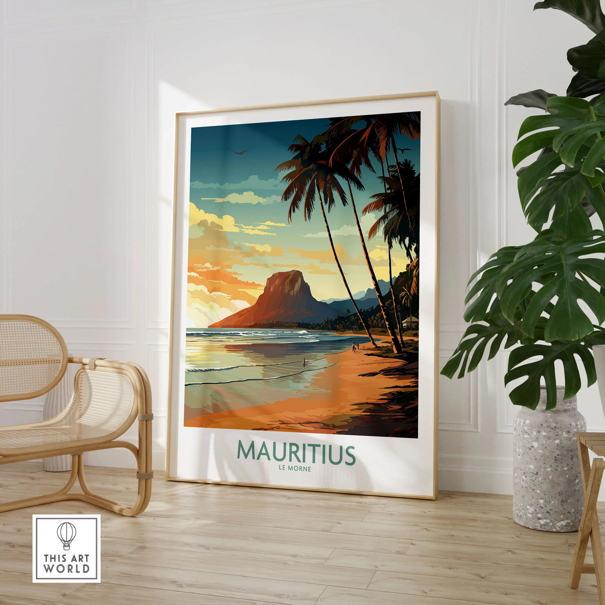 Mauritius Le Morne Print in a large natural wood frame leaning in a room with a rattan chair and monstera plant