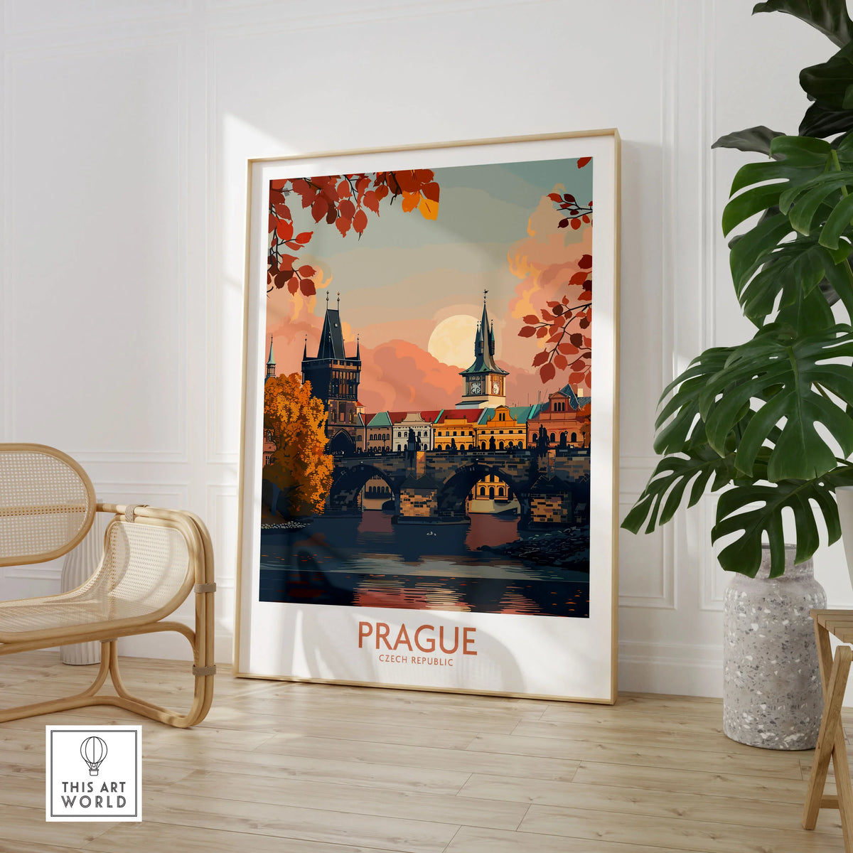 Prague Travel Print in a large natural wood frame leaning in a room with a rattan chair and monstera plant