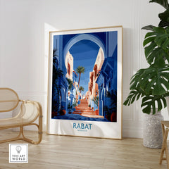 Rabat Morocco Blue Alleyway Wall Art — a blue-washed medina lane and stone steps seen through a horseshoe arch, shown as large framed print room setting chair plant