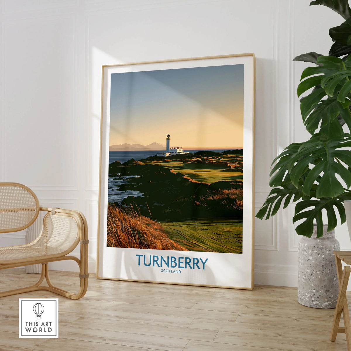 Turnberry Scotland Rocky Shore Wall Art — the Turnberry lighthouse above a rocky shore with the Arran hills beyond, shown as large framed print room setting chair plant