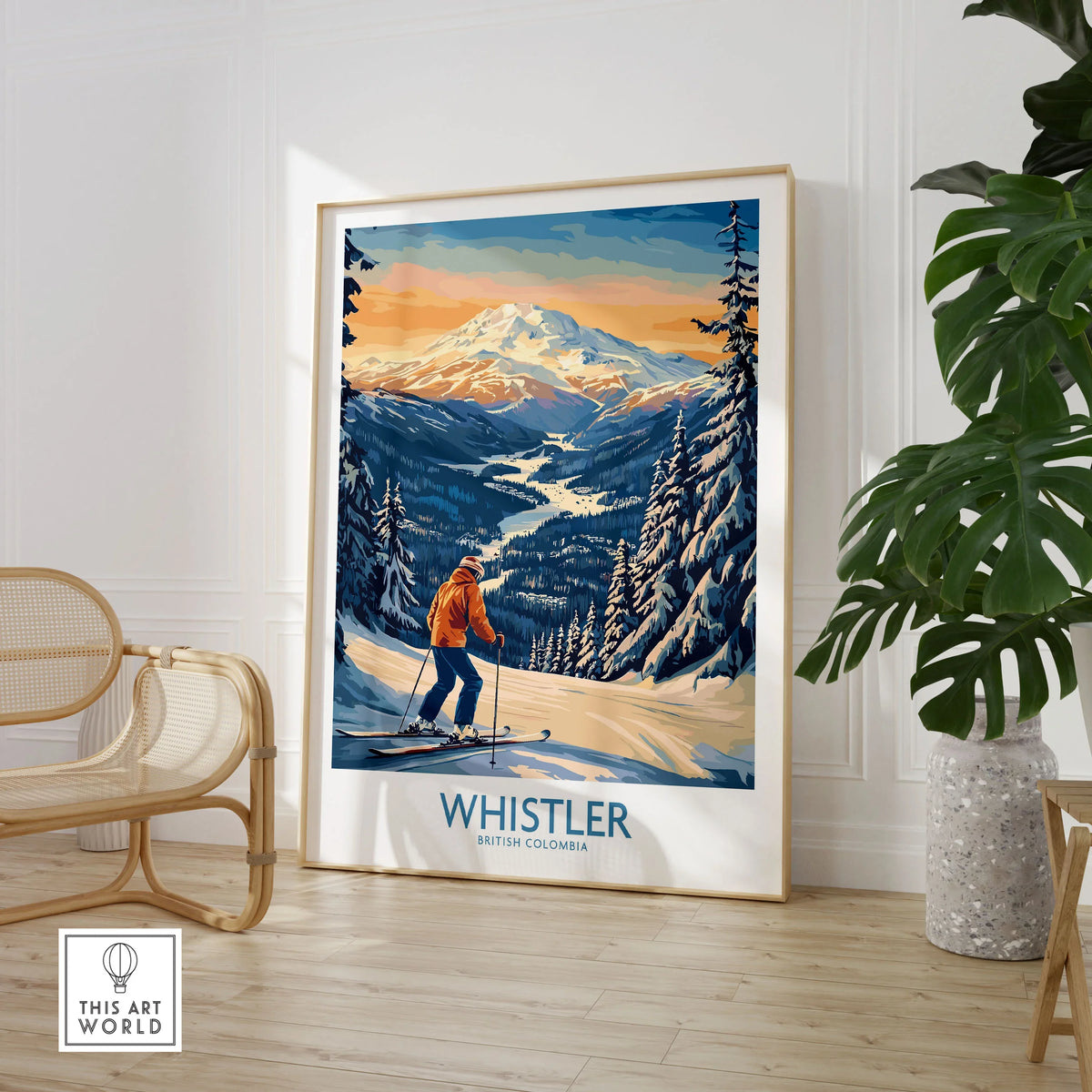 Whistler Ski Print - British Columbia in a large natural wood frame leaning in a room with a rattan chair and monstera plant