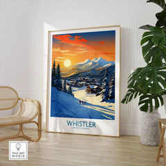 Whistler Wall Art Ski Poster in a large natural wood frame leaning in a room with a rattan chair and monstera plant