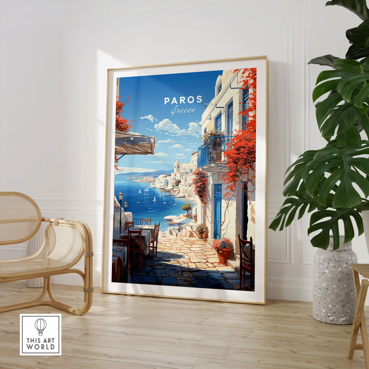Paros Travel Poster in a large natural wood frame leaning in a room with a rattan chair and monstera plant
