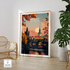 Prague Art Print in a large natural wood frame leaning in a room with a rattan chair and monstera plant