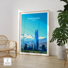 Santiago Travel Poster - Chile in a large natural wood frame leaning in a room with a rattan chair and monstera plant