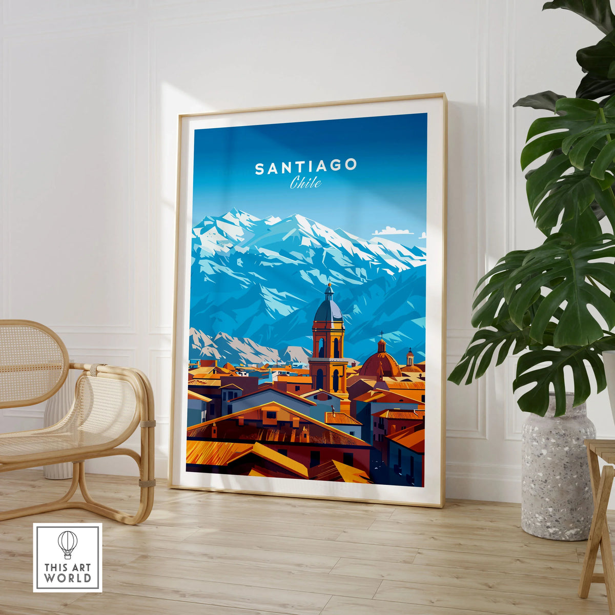 Santiago Travel Print - Chile Poster in a large natural wood frame leaning in a room with a rattan chair and monstera plant