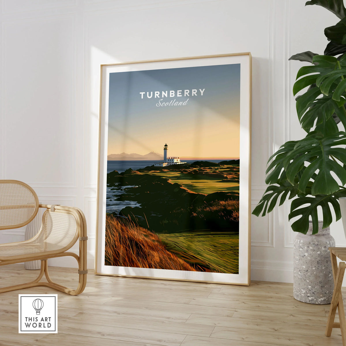 Turnberry Scotland Lighthouse Travel Poster — the Turnberry lighthouse above a rocky shore with the Arran hills beyond, shown as large framed print room setting chair plant