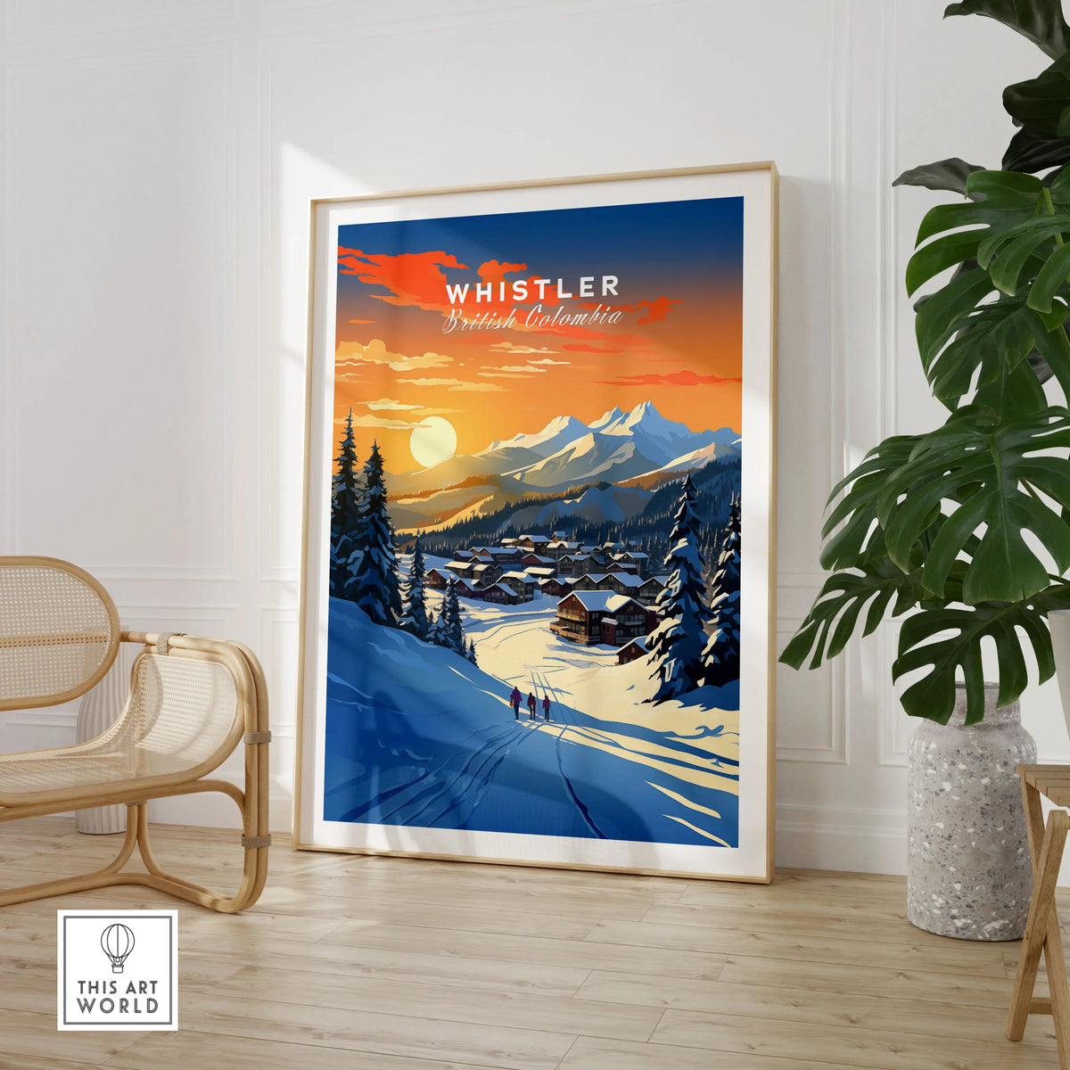 Whistler Wall Art Ski Print in a large natural wood frame leaning in a room with a rattan chair and monstera plant