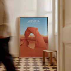 Framed Arches National Park poster on floor in modern room with man walking past.
