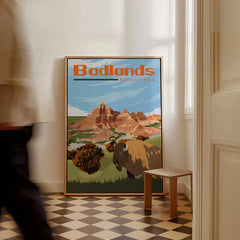 Framed Badlands National Park travel poster with buffalo and mountains on floor in bright room