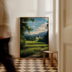 Framed Balmoral Castle travel poster leaning on wall in modern hallway, person walking past