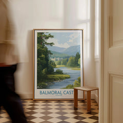 Framed Balmoral Castle travel poster with river landscape, set on floor in bright hallway.