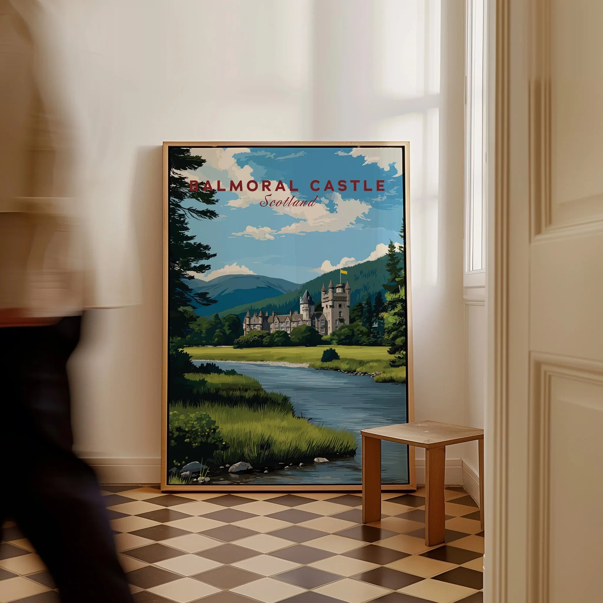 Framed Balmoral Castle travel poster on checkered floor, man walking past in bright hallway