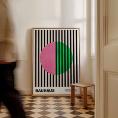 Bauhaus Exhibition Prints - Split Circle Abstract Art Print Pink Green Stripes displayed in a stylish interior with striped background.