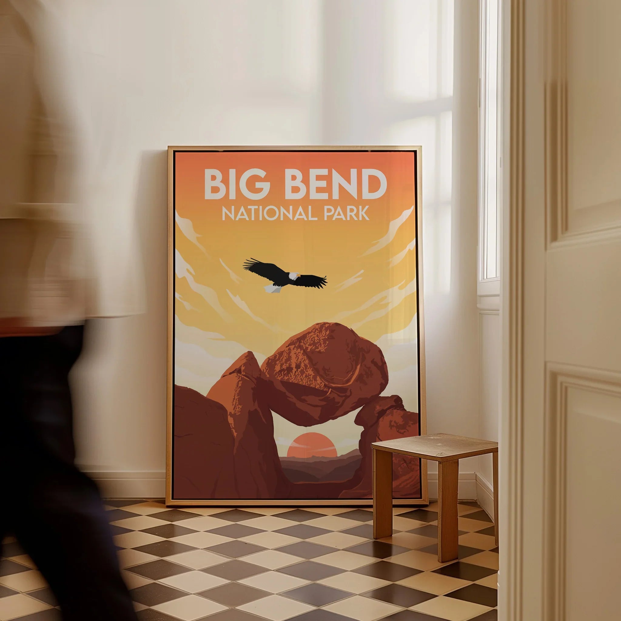 Framed Big Bend National Park travel poster with eagle and desert rocks on floor in sunlit hallway.