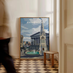 Framed Birmingham travel poster with city skyline art on floor in modern hallway