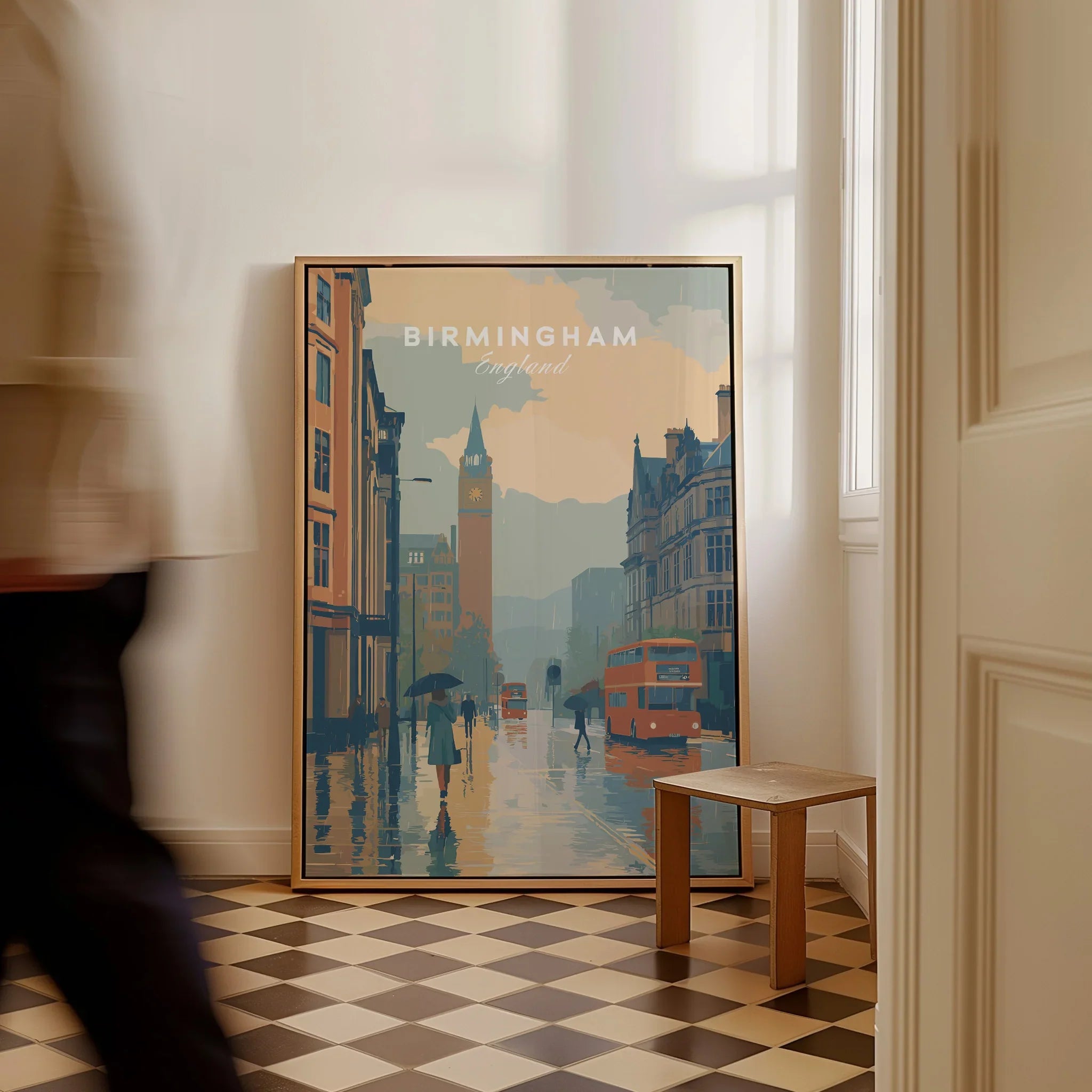 Framed Birmingham England cityscape travel poster on checkered floor, man walking past.