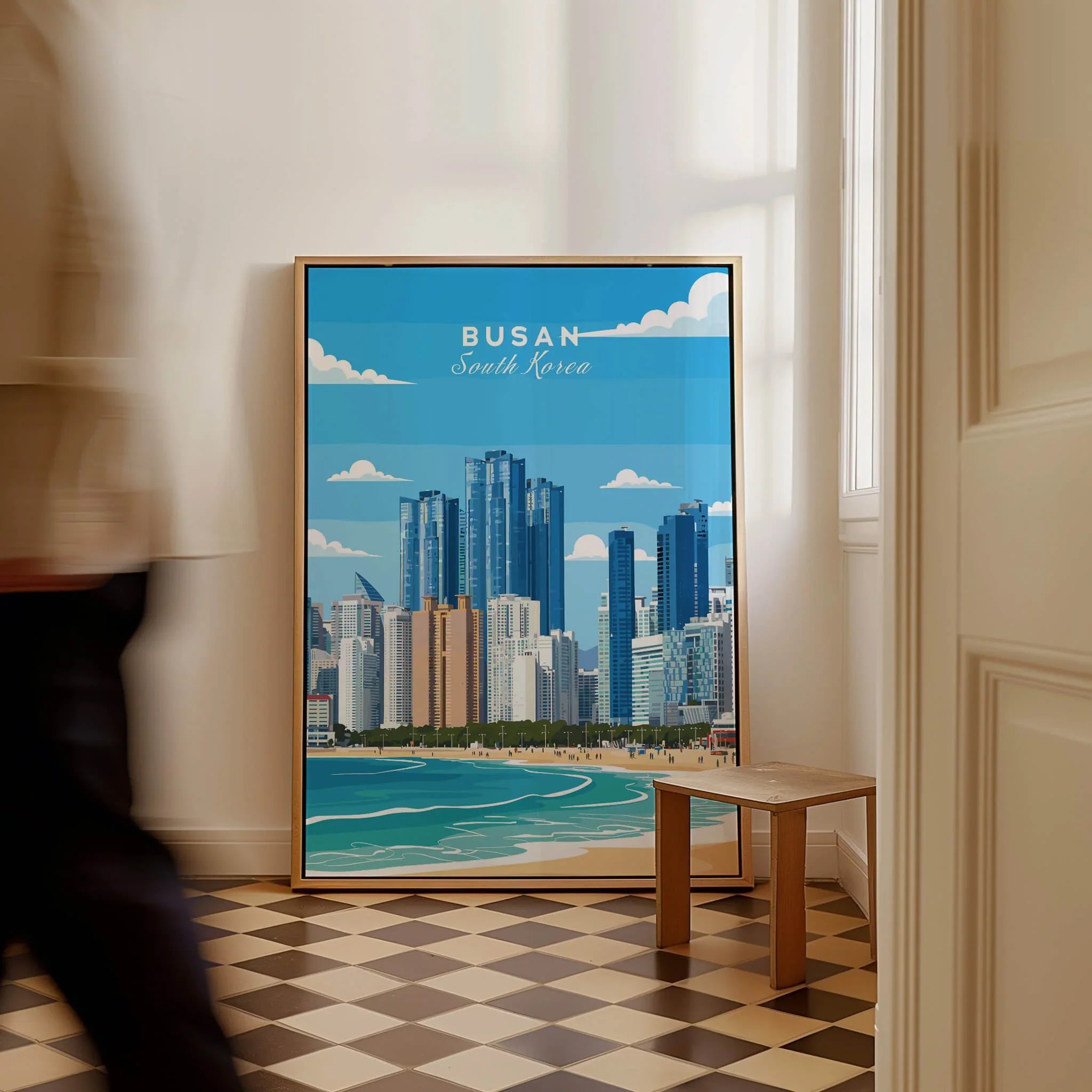 Framed Busan South Korea city skyline travel poster on floor in bright hallway