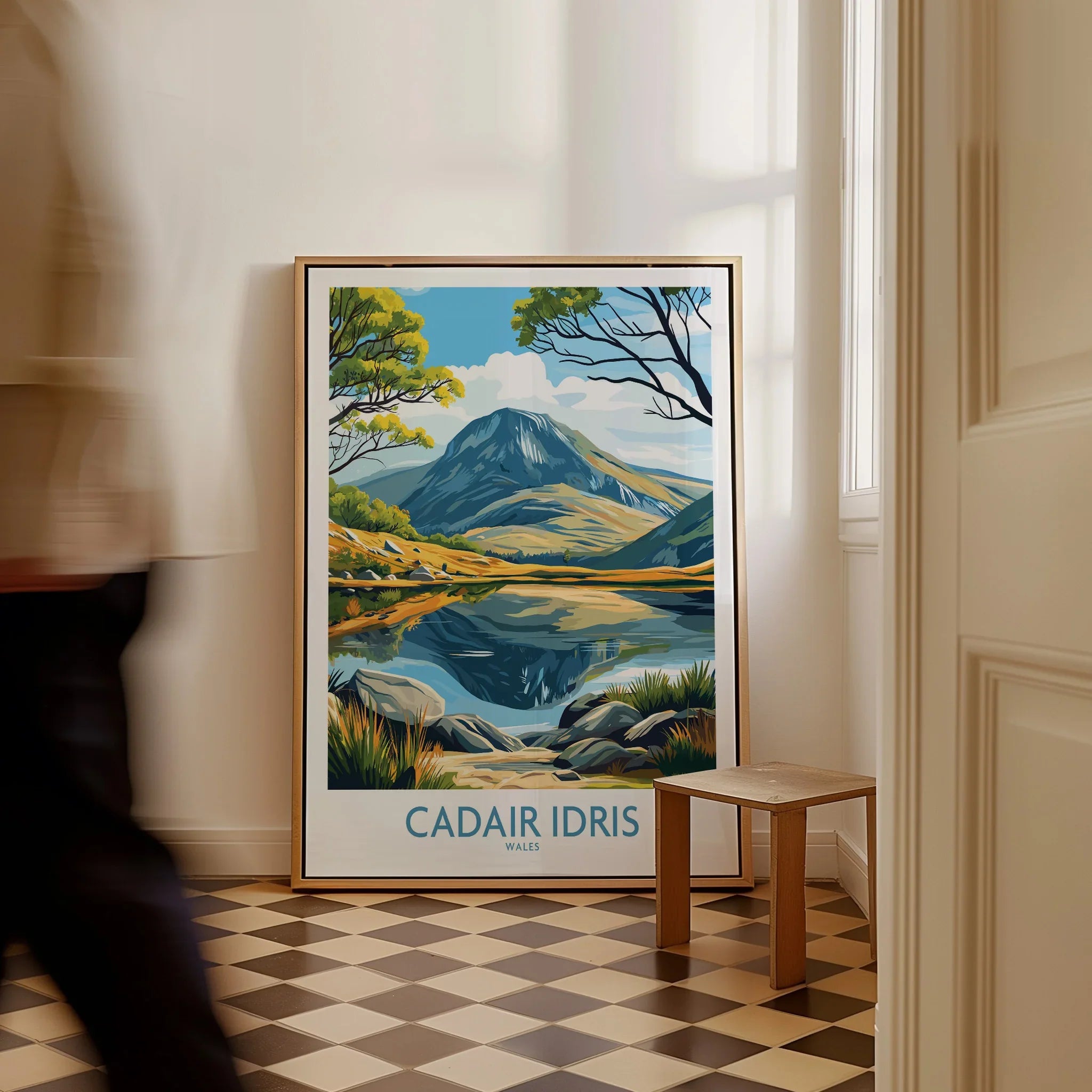Framed Cadair Idris travel poster with mountain landscape art on floor near hallway.