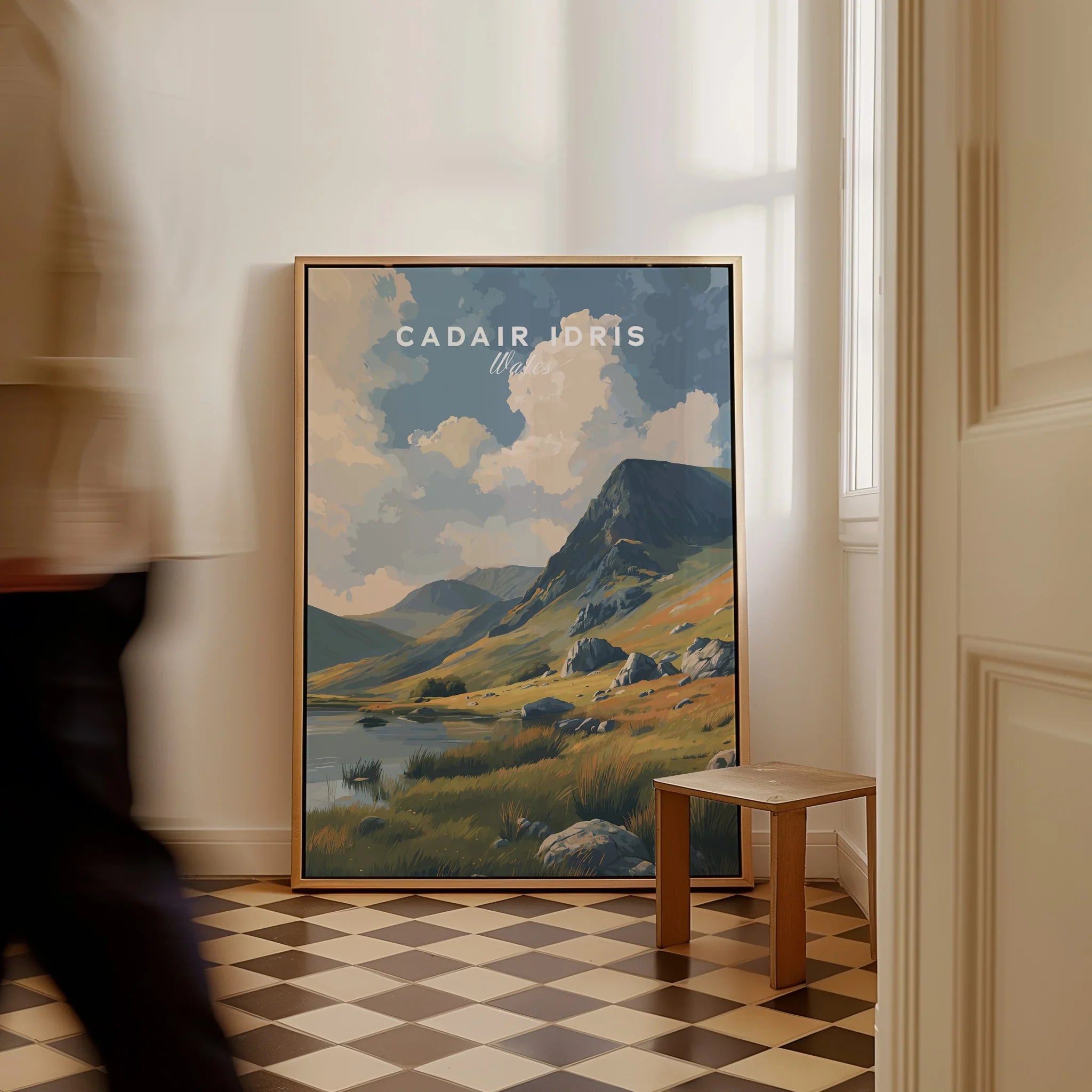 Framed Cadair Idris travel art print leaning on floor in bright, modern room with checkered tiles.