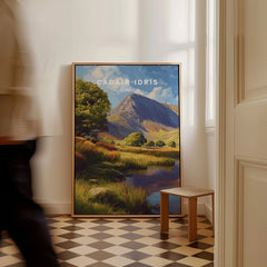 Framed Cadair Idris travel poster print on floor in bright hallway, man walking past.