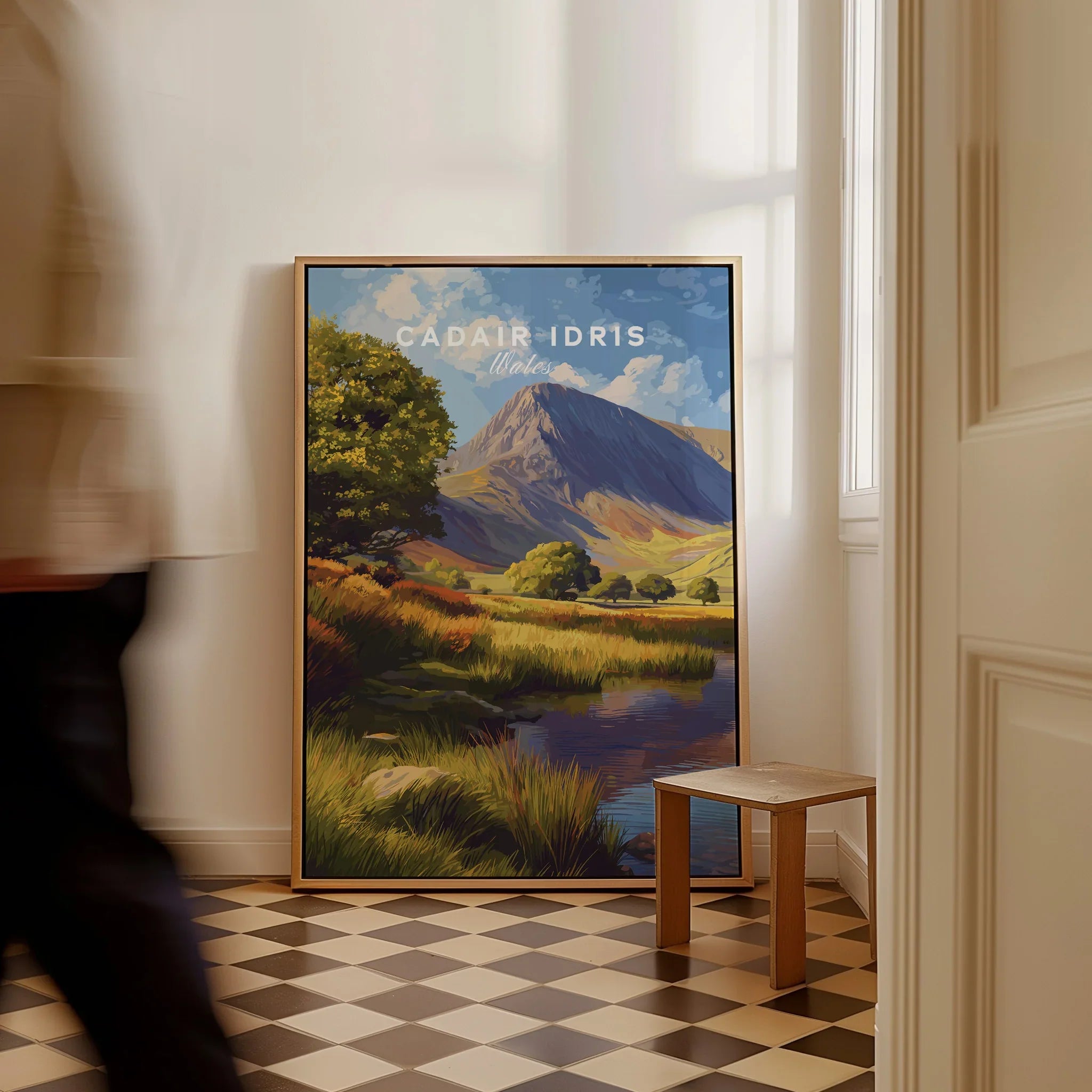 Framed Cadair Idris travel poster print on floor in bright hallway, man walking past.