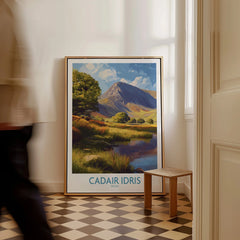 Framed Cadair Idris travel poster with mountain landscape art on hallway floor, man walking past.