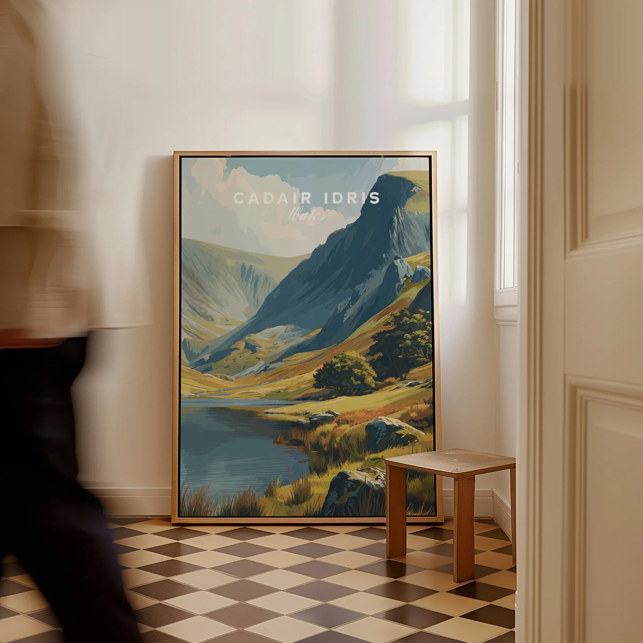 Framed Cadair Idris Wales travel poster with mountain landscape on floor, man walking past