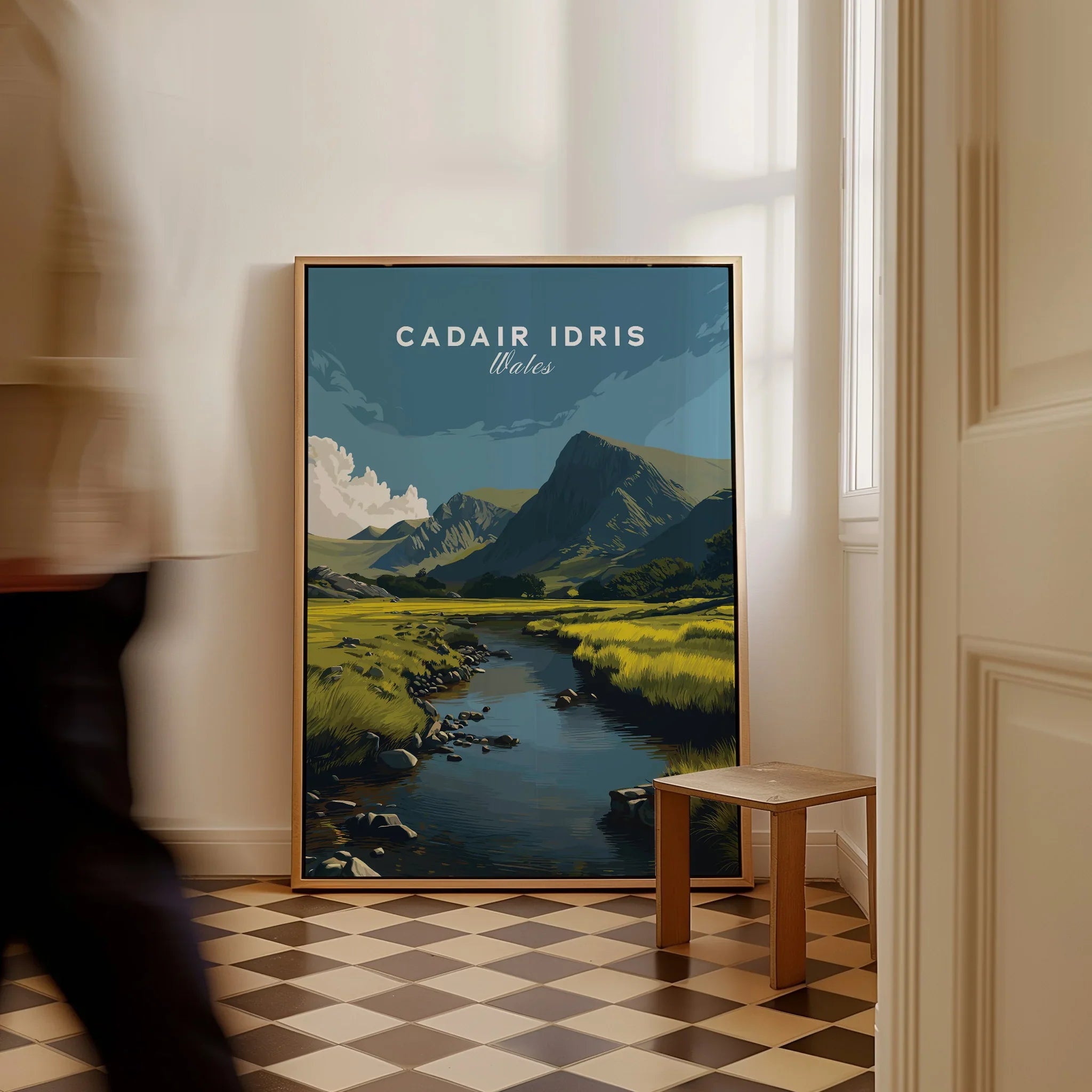 Framed Cadair Idris Wales travel poster with mountain landscape art on floor, person walking by