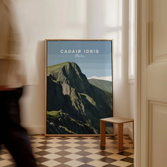 Framed Cadair Idris Wales travel poster leaning on floor in sunlit hallway, man walking past