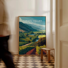 Framed Carmel Valley California travel poster with vineyard art on floor, man walking past