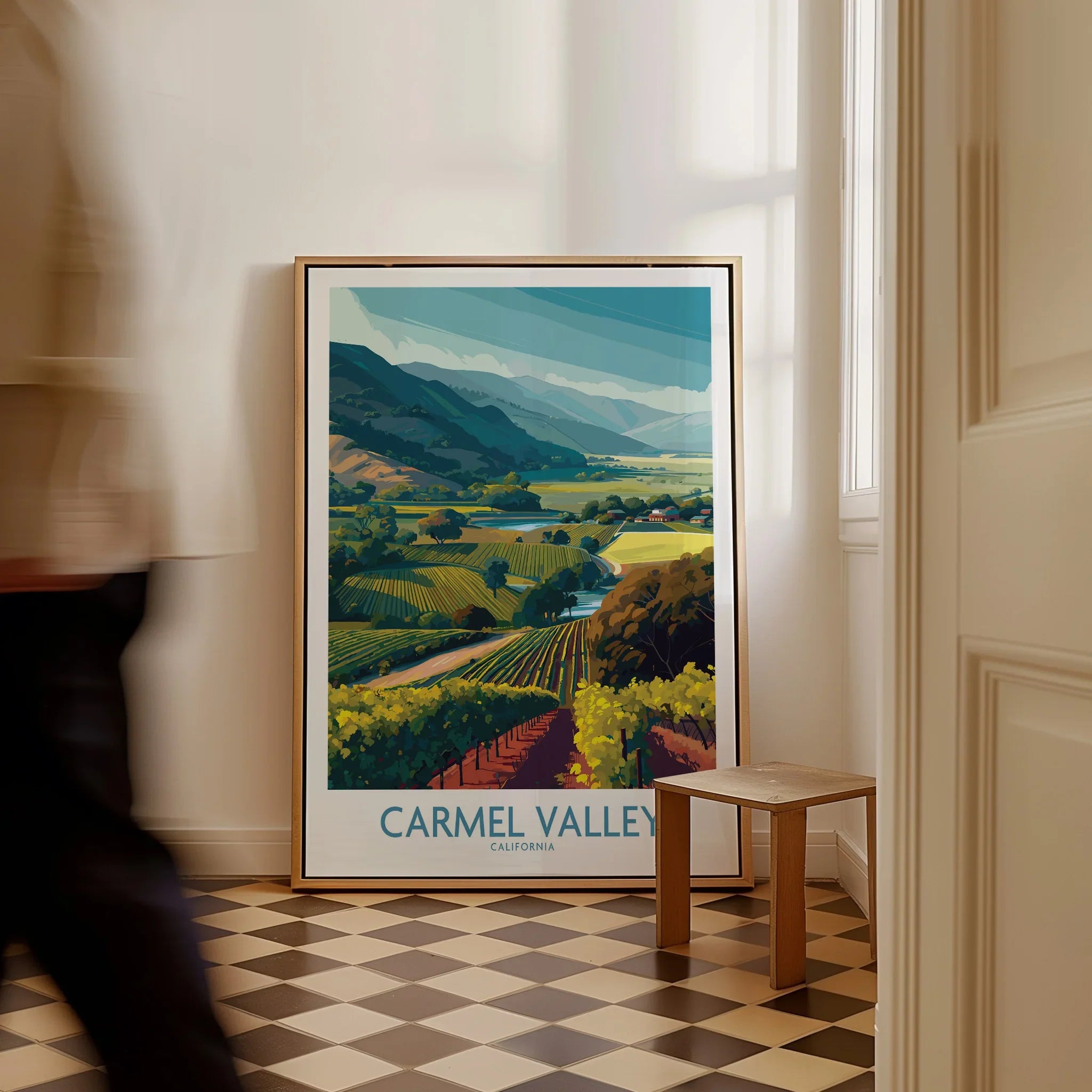 Carmel Valley California travel poster in frame on checkered floor, man walking past.