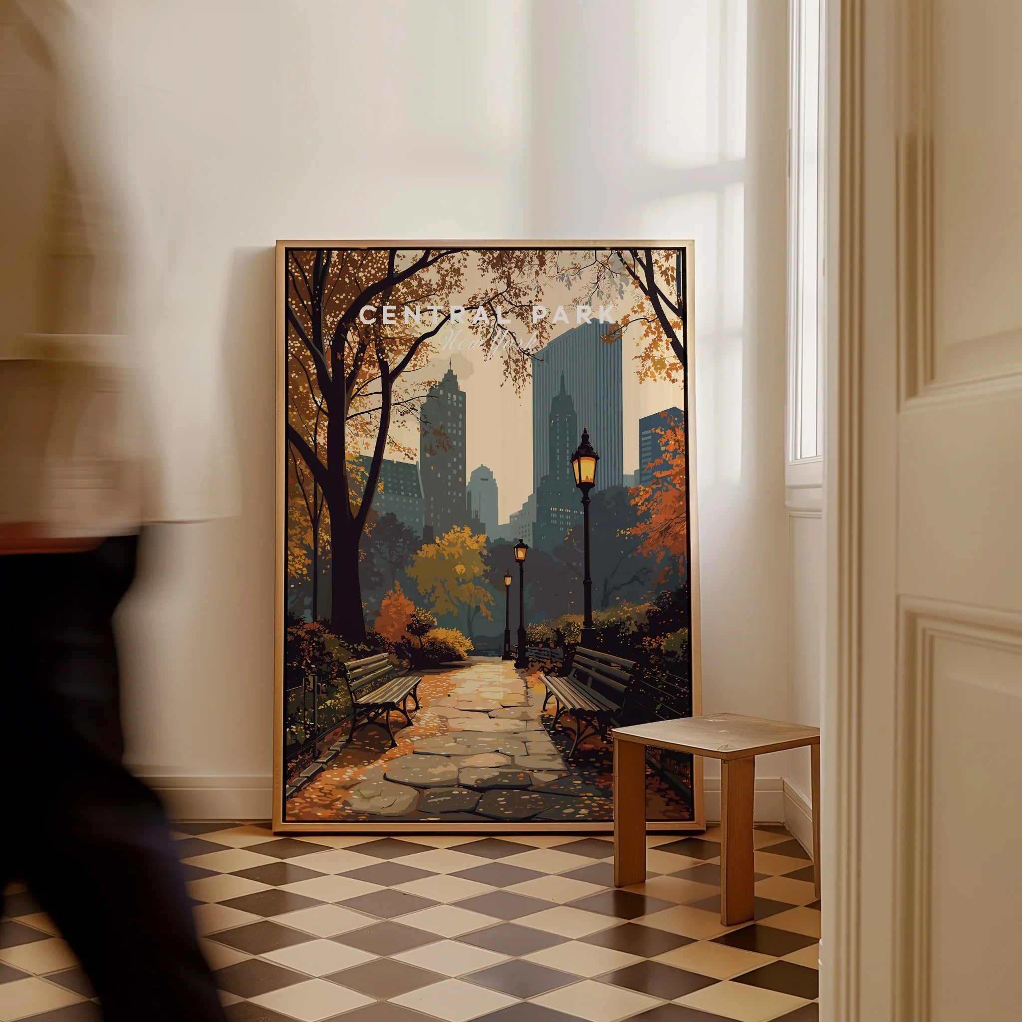 Framed Central Park travel poster with autumn city skyline, leaning on a wall indoors.