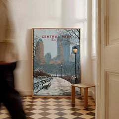 Framed Central Park New York winter cityscape wall art on floor with man walking past