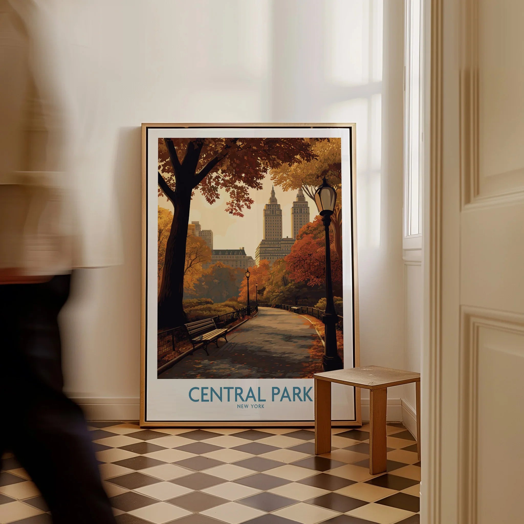 Framed Central Park New York wall art with fall colors on a checkered floor, man walking past.