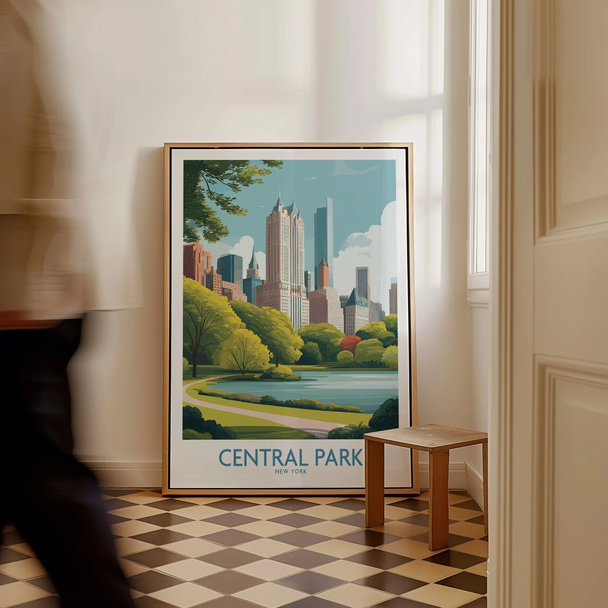 Framed Central Park New York travel poster with city skyline art on floor near a stool