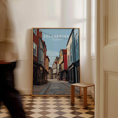 Colchester England travel poster framed on floor, man walking past in modern home